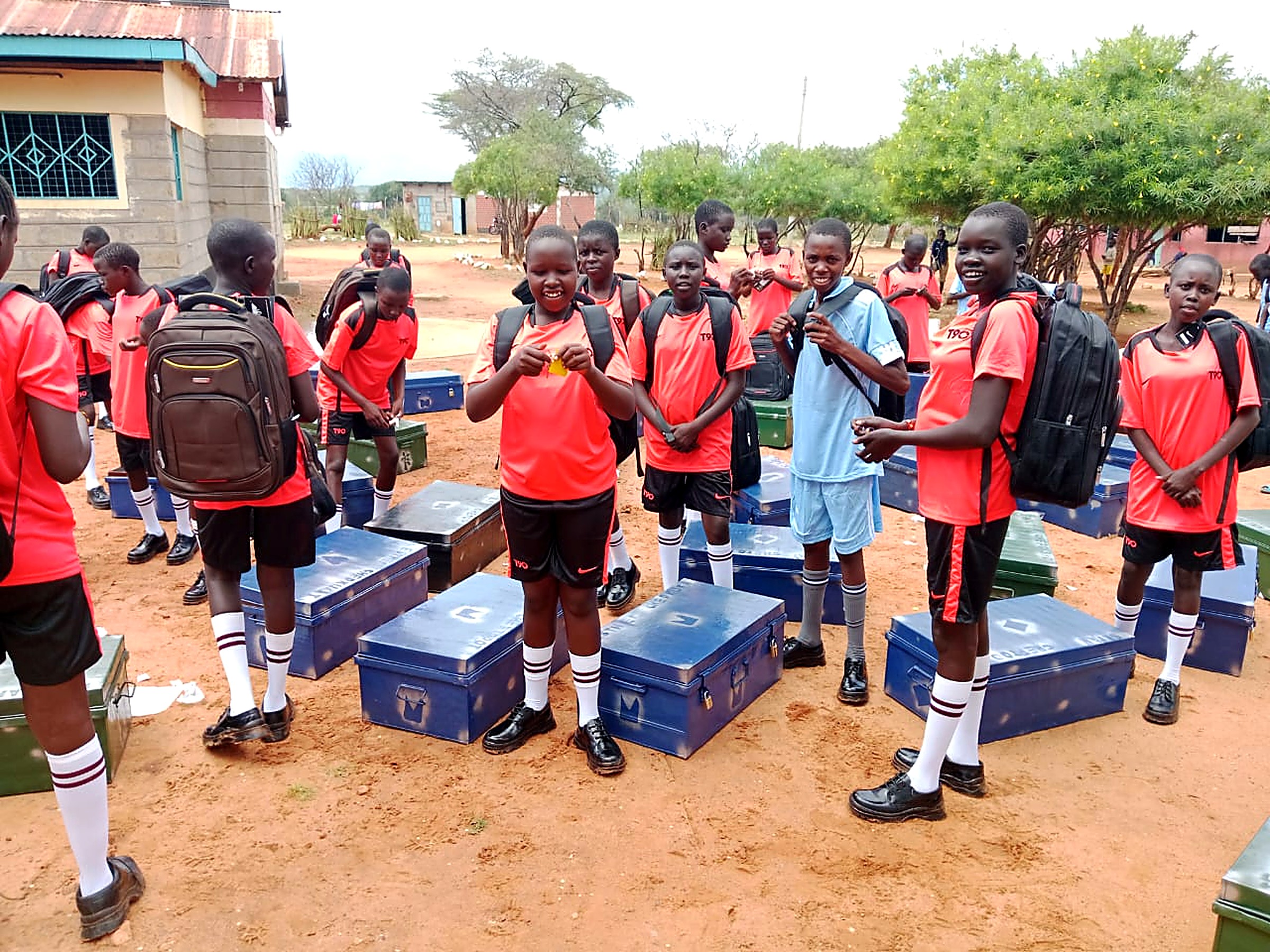 Students in sports kit standing beside new metal boxes and school backpacks