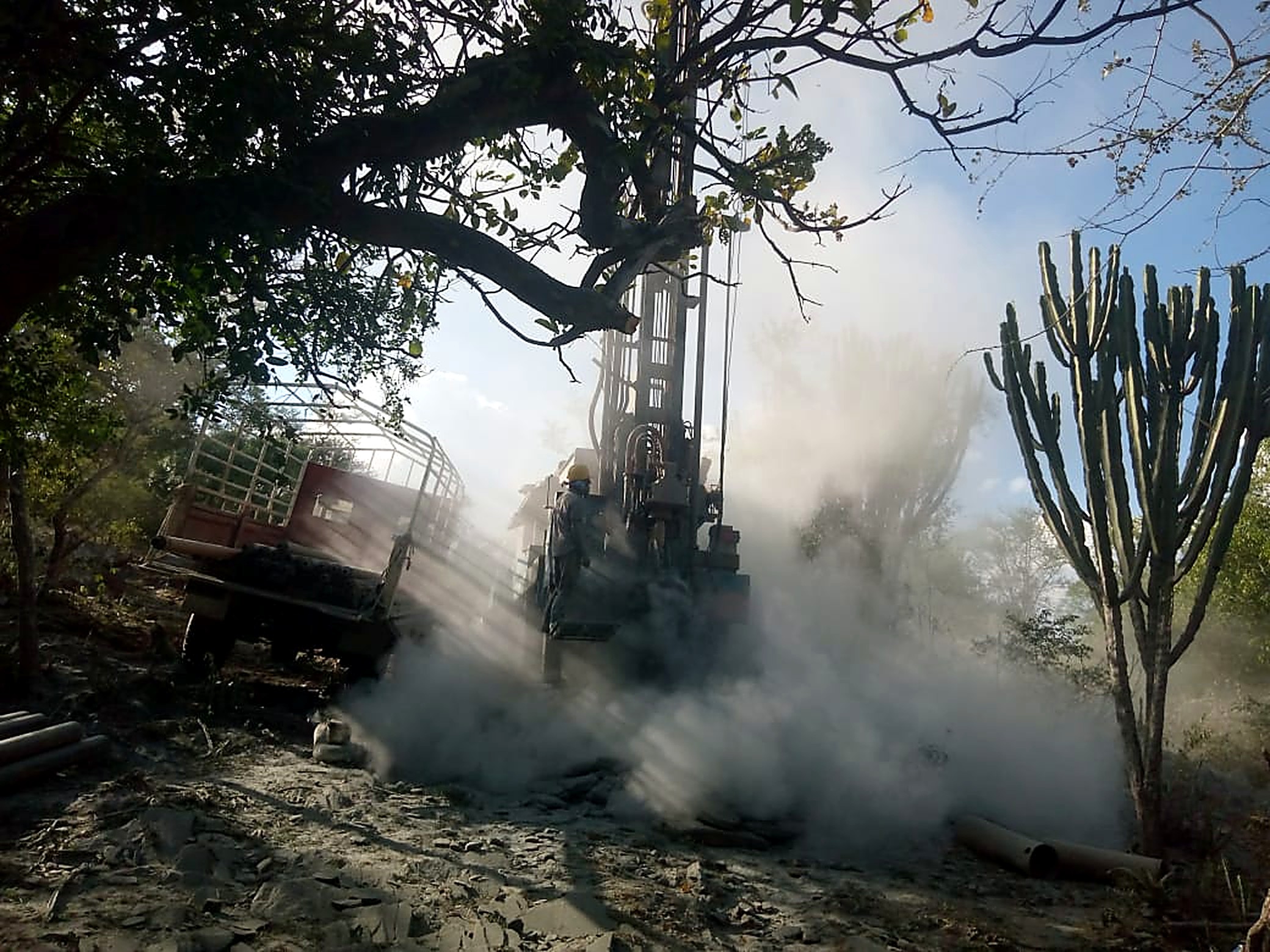 Drilling rig at work in dusty bushland during borehole exploration