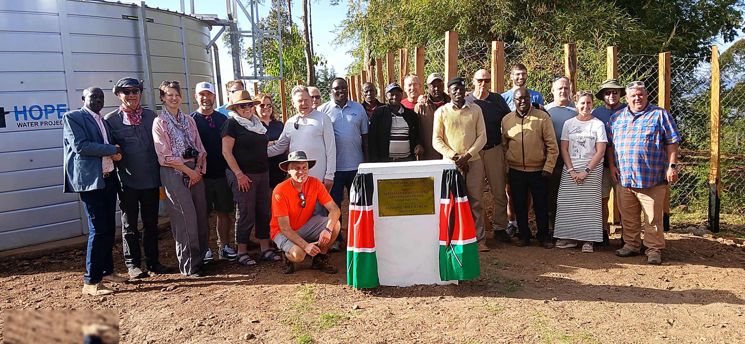 Kenyan and international partners standing beside the dedication plaque of the Sina Water Project