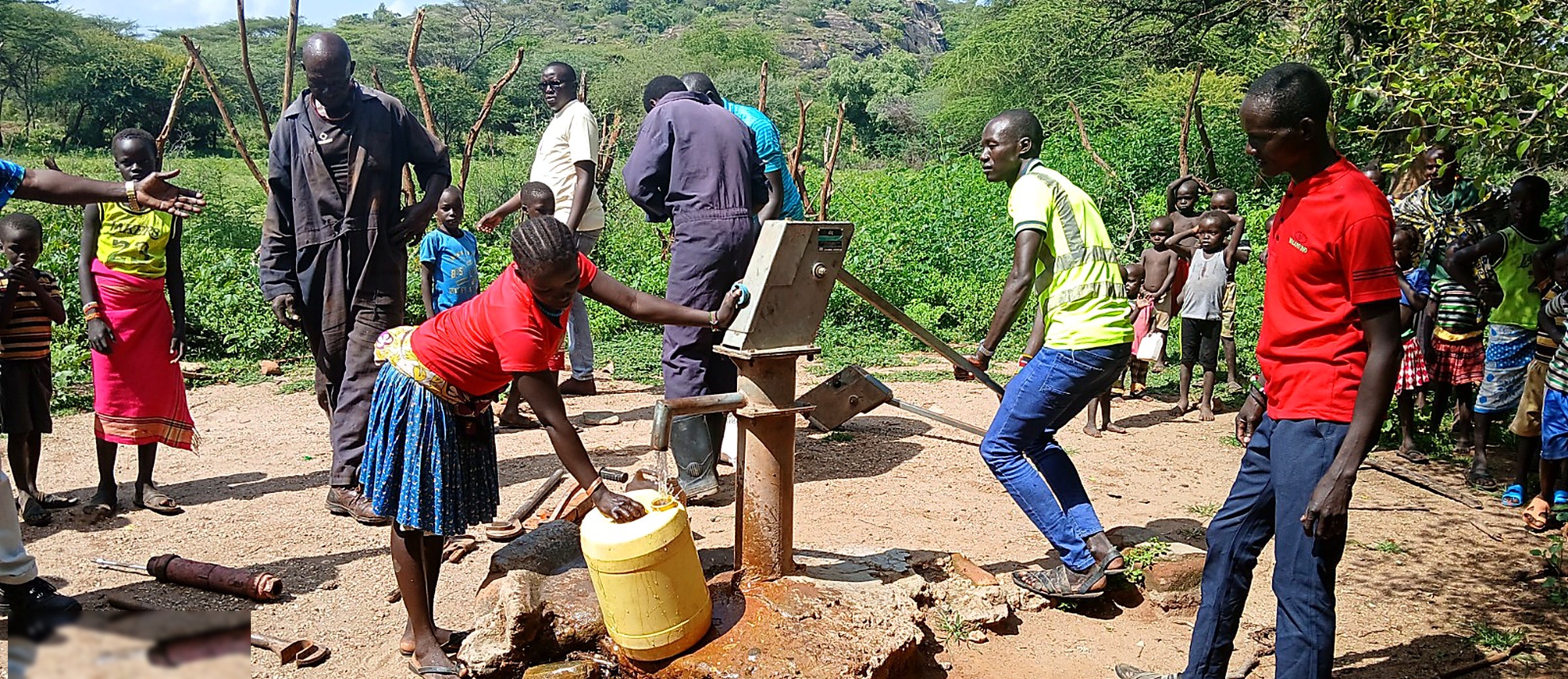 A woman filling a jerrycan with clean water from a hand pump while community members look on