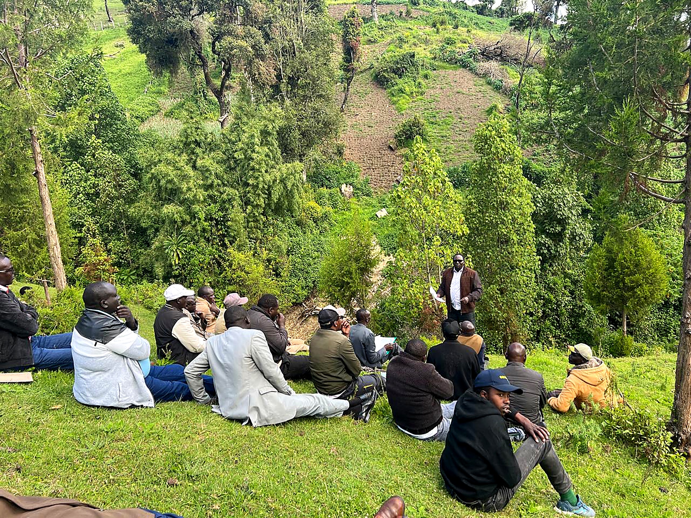 Men seated on a hillside listening to a leader teaching in the open air