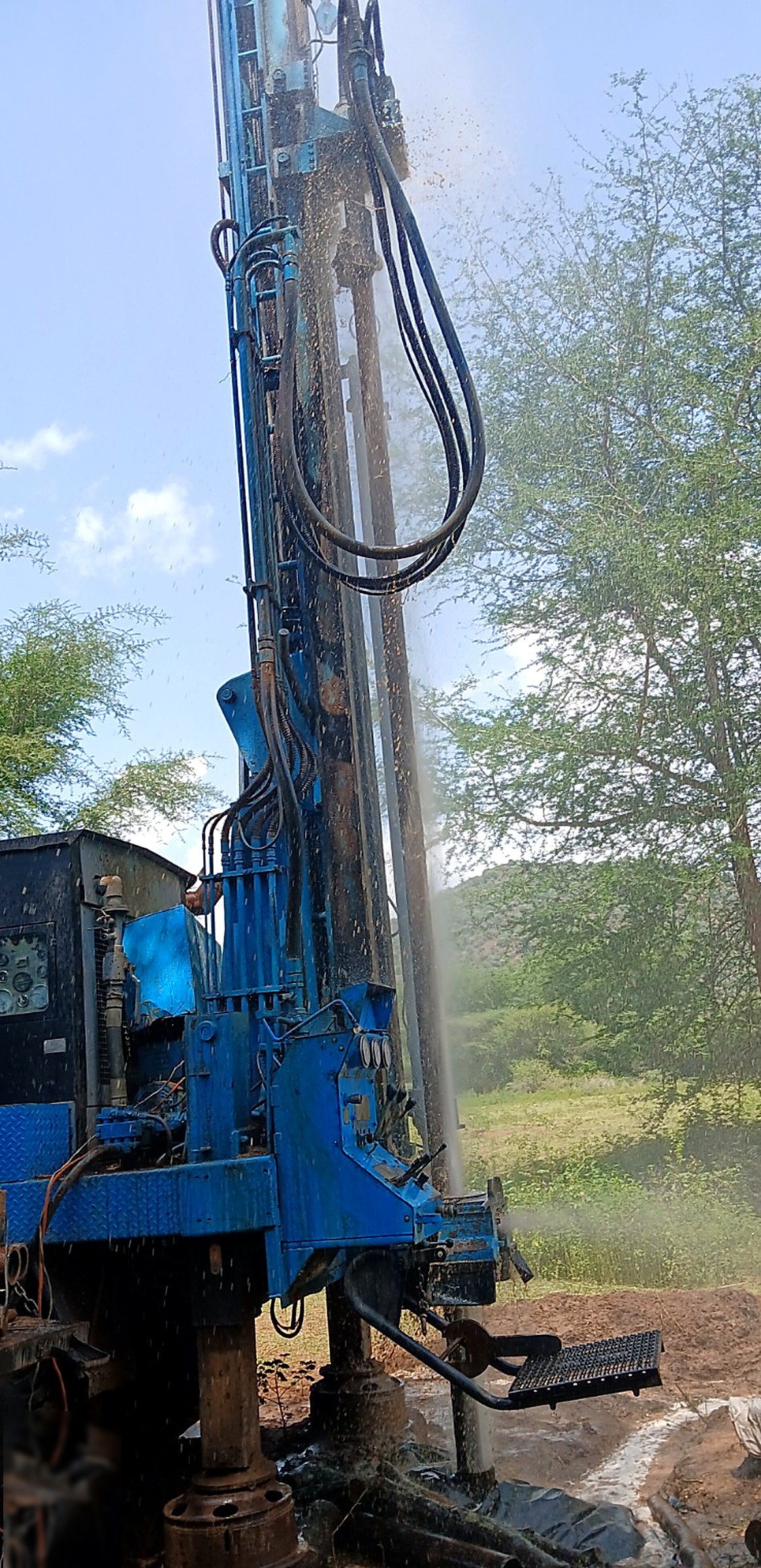 Drilling rig striking water, with spray rising from the borehole